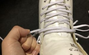 スケート靴の紐を引っ張っている